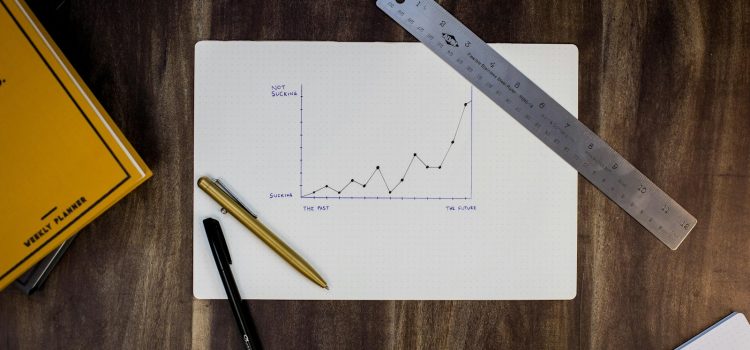A hand-drawn line graph on paper with a ruler and pens