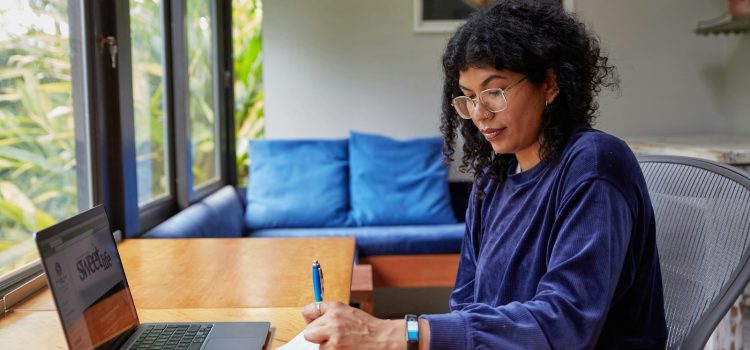 Writing Marketing Emails People Actually Open and Read A woman writing notes beside a laptop at a table